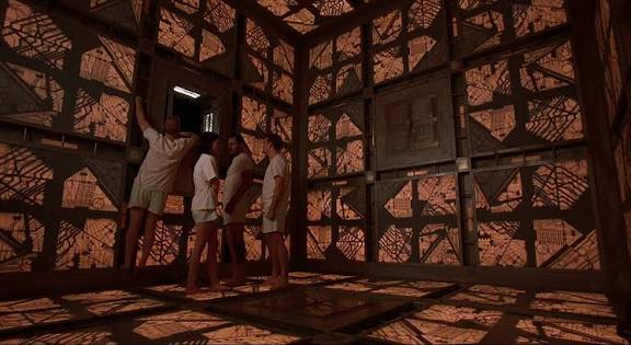 Children exploring a dark, eerie room with shadowy tree patterns on the walls.