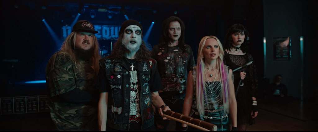 Group of five horror-themed characters in dark costumes at a concert.
