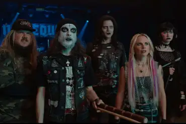 Group of five horror-themed characters in dark costumes at a concert.