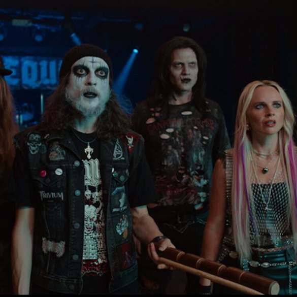 Group of five horror-themed characters in dark costumes at a concert.