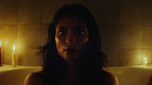 Dark, moody image of a woman with candles in the background for horror film atmosphere.