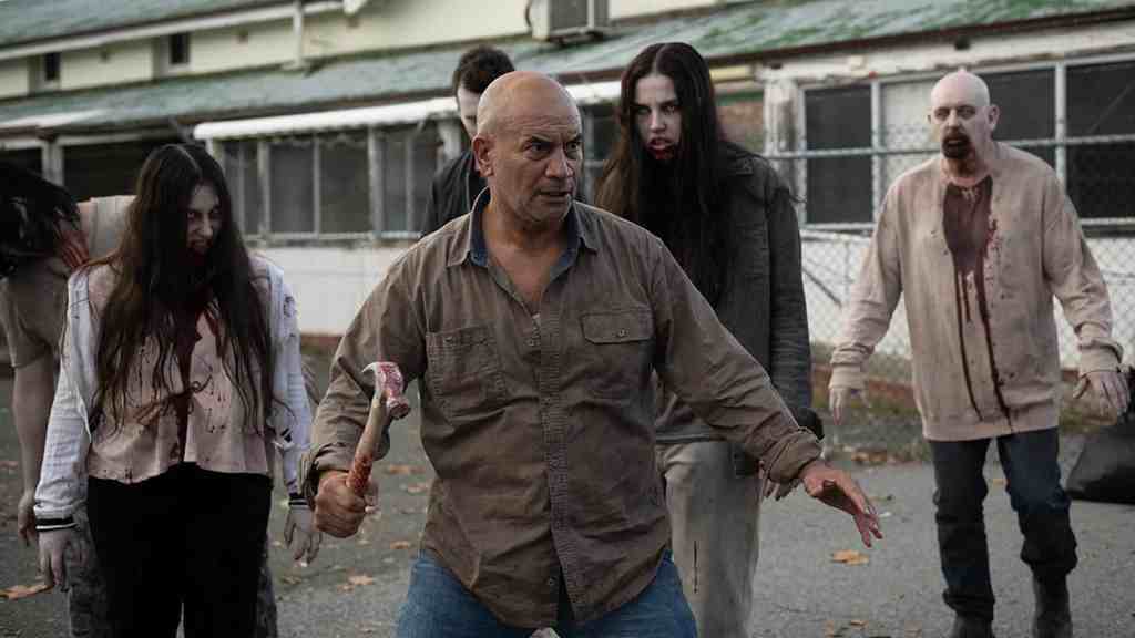 Zombies and a man with an axe in a horror scene from Dead Howling trailer.