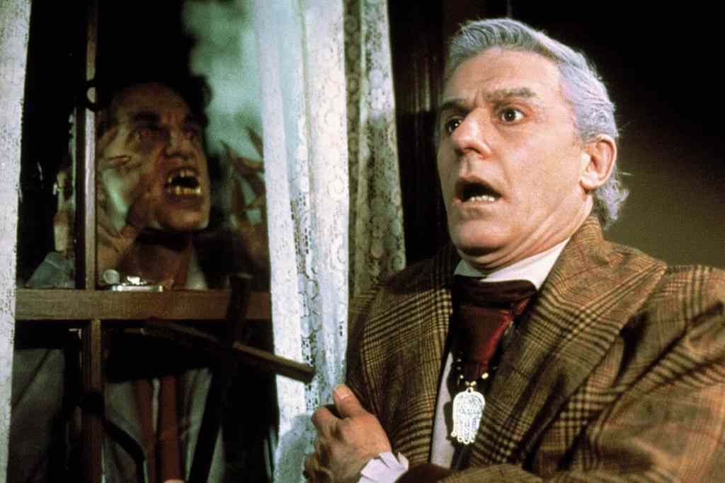 Classic horror scene with a terrified man and a zombie behind bars.