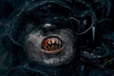 Scary creature with decayed face and sharp teeth, dark and eerie atmosphere.