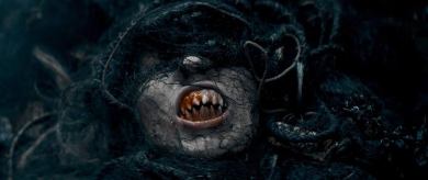 Scary creature with decayed face and sharp teeth, dark and eerie atmosphere.