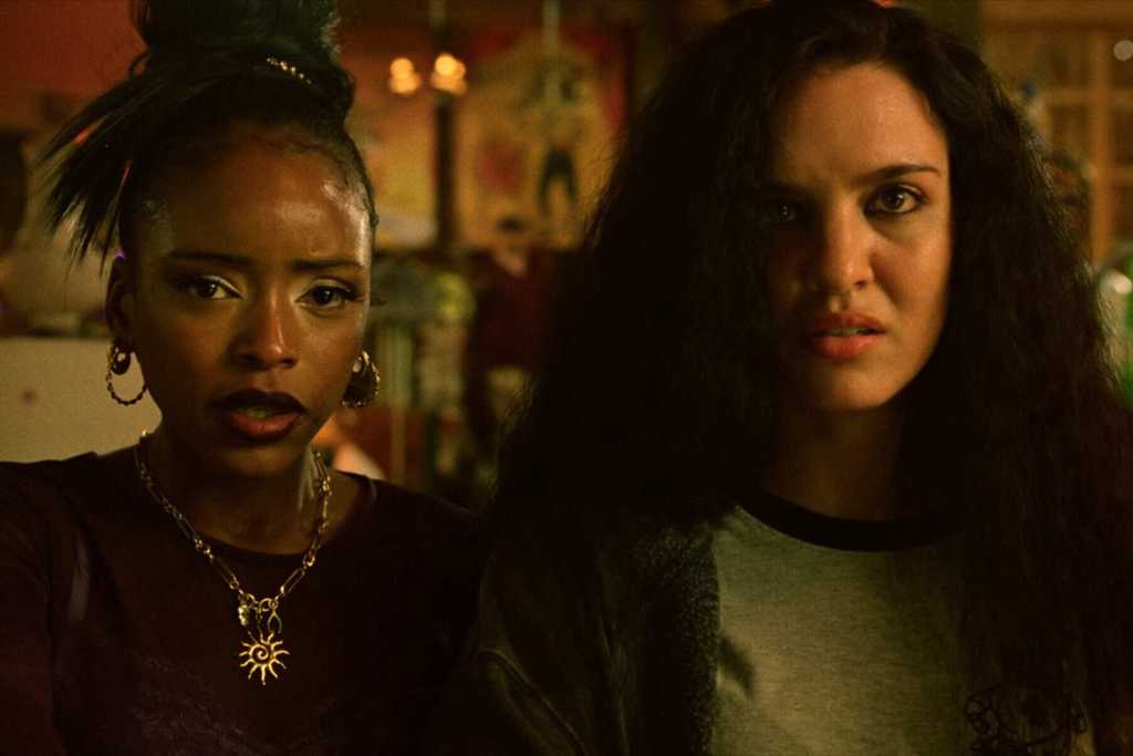 Two women with intense expressions in a dimly lit setting.