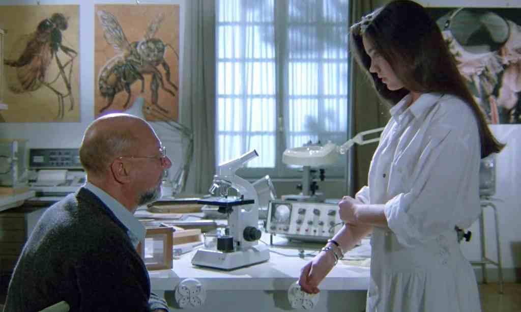 Scientist examining a patient's arm in a laboratory setting from Horror History - The Late Eighties.