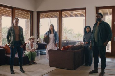 Diverse group of five people in a modern living room with large windows.