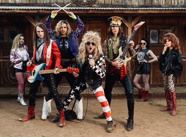 Rock band women posing with guitars and microphone outdoors in vintage setting.